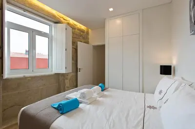 a bedroom with a white bed and a window at Estrela de Gaia Apartments in Vila Nova de Gaia