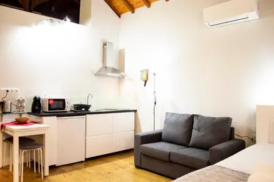 a room with a bed and a chair and a kitchen at Old City Oporto in Porto