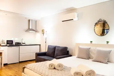 a white bedroom with a bed and a chair at Old City Oporto in Porto