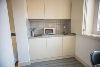 a small kitchen with white cabinets and a microwave at Oporto Cool - Praça da Batalha in Porto