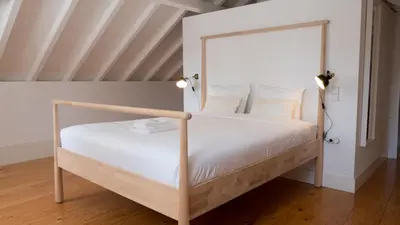 a white bed with a wooden frame in a room at APOSENTUS - Architect and design apartment in Porto