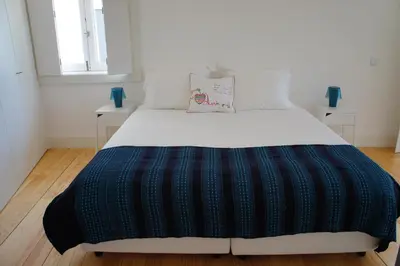 a bed with a black and blue blanket on it at Alfandega Apartments in Porto