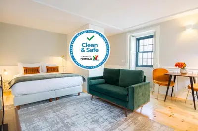 a bedroom with a bed and a green chair at Barão Oporto Apartments in Porto