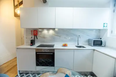 a kitchen with white cabinets and a dog laying on the floor at Loft da Sé by Porto City Hosts in Porto