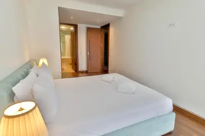 a bedroom with a large white bed and a lamp at Afurada premium apartment by Porto City Hosts in Vila Nova de Gaia