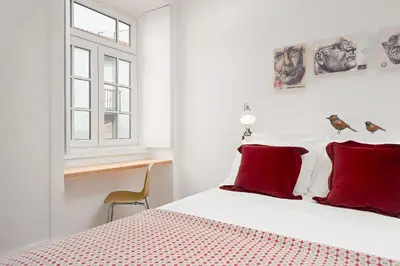 a bedroom with a bed with red pillows and a window at Oporto Classic Pàtio in Porto