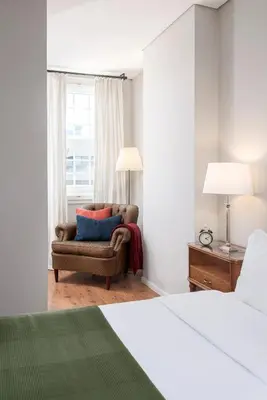 a bedroom with a bed and a chair and a window at B The Guest Downtown in Porto
