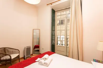 a bedroom with a bed and a chair and a window at Porto by the River 1 in Porto
