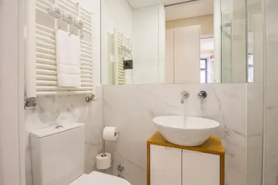 a white bathroom with a sink and a toilet at Tailor's Apartment in Porto
