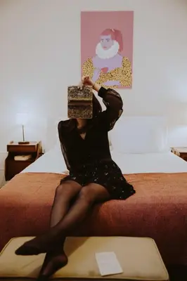 a woman sitting on a bed with a box on her head at aDuquesa - GuestHouse in Porto