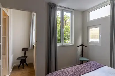 a bedroom with a bed and two windows at aDuquesa - GuestHouse in Porto