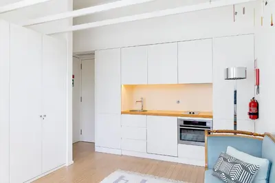 a kitchen with white cabinets and a blue chair at The Art Porto - Holiday Homes in Porto