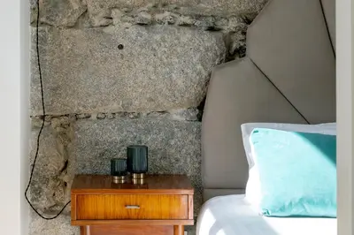 a bed with a nightstand next to a stone wall at The Art Porto - Holiday Homes in Porto