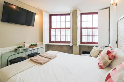 a bed with white sheets and pillows at Charming Studio in Historic Downtown in Porto