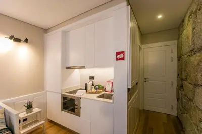 a small kitchen with white cabinets and a sink at Oldtown Studio in Porto