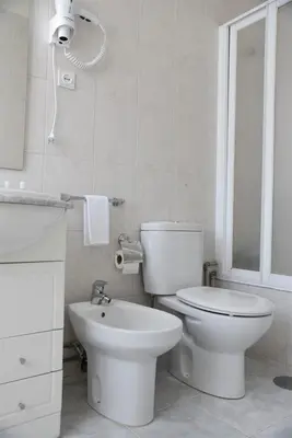 a white bathroom with a toilet and a sink at Hotel Visconde in Porto