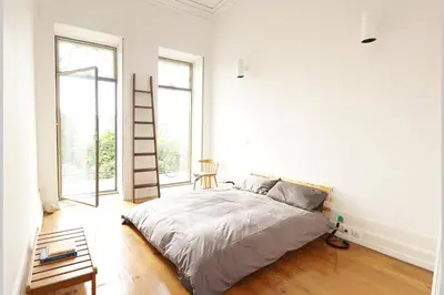 a bedroom with a bed in a room with windows at Alegria 1º in Porto