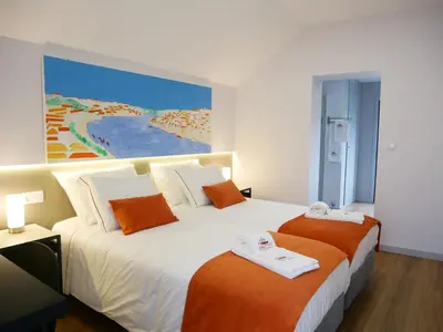 two beds in a hotel room with a painting on the wall at Serra do Pilar Porto Suites in Vila Nova de Gaia