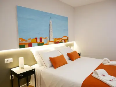 a white bed with orange pillows in a room at Serra do Pilar Porto Suites in Vila Nova de Gaia