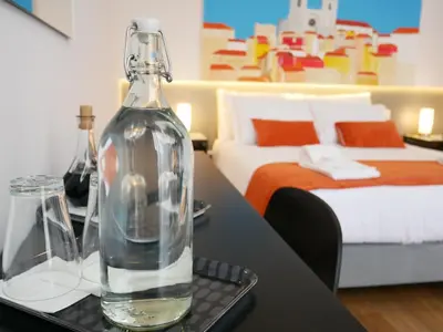 a glass bottle sitting on a table next to a bed at Serra do Pilar Porto Suites in Vila Nova de Gaia