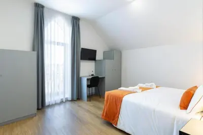 a bedroom with a bed and a desk and a window at Serra do Pilar Porto Suites in Vila Nova de Gaia