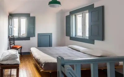 a bedroom with a blue bed and two windows at São Miminho 3º in Porto
