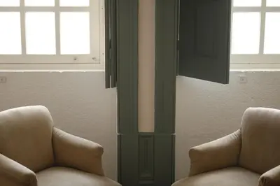 a living room with two chairs and two windows at São Miminho 3º in Porto