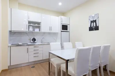 a kitchen with white cabinets and a table and white chairs at Yellow Tiles by PCALE in Porto