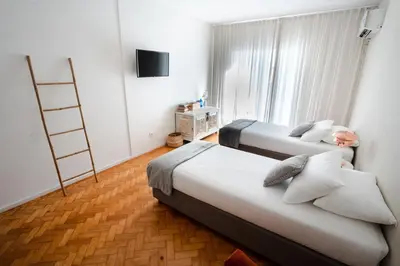 two beds in a hotel room with a television at Alegria Cozy com Terraço - Centro do Porto in Porto