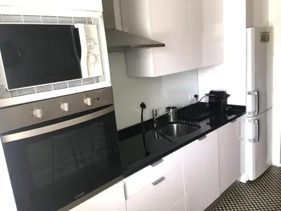 a white kitchen with a sink and a microwave at Alegria Cozy com Terraço - Centro do Porto in Porto