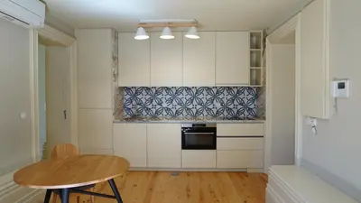 a kitchen with white cabinets and a wooden table at Oporto Maison Palace in Porto