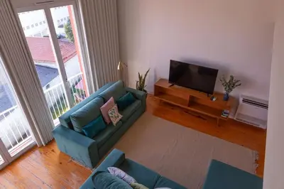 a living room with a blue couch and a flat screen tv at Batalha Mezzanine Penthouse in Porto