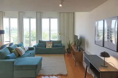 a living room with two blue couches in front of windows at Batalha Mezzanine Penthouse in Porto