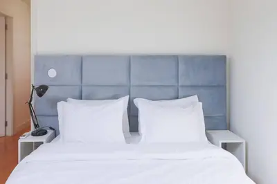 a bed with two white pillows and a blue headboard at Batalha Mezzanine Penthouse in Porto