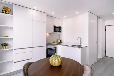 a kitchen with white cabinets and a wooden table at BBA Apartments Palácio II - Garden View, Gym & Free Parking in Porto