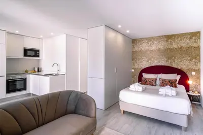 a bedroom with a bed and a couch and a kitchen at BBA Apartments Palácio II - Garden View, Gym & Free Parking in Porto