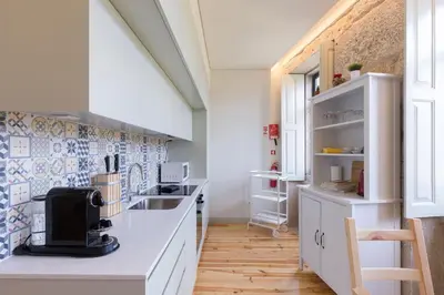 a kitchen with white counters and blue tiles on the wall at Luz & Alegria Place! in Porto