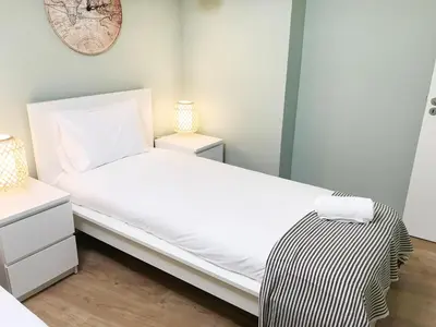 a bedroom with a white bed and a clock on the wall at Little Tower in Porto