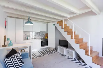 a living room with a staircase and a kitchen at Loureiro Villas in Porto