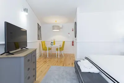 a living room with a tv and a table with yellow chairs at Loureiro Villas in Porto