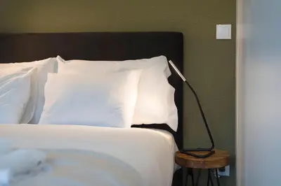 a bed with white pillows and a lamp on a table at LovelyStay - Modern Loft with Gym & Free Parking minutes away from CBD in Porto