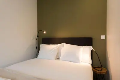 a bedroom with a bed with white sheets and a lamp at LovelyStay - Modern Loft with Gym & Free Parking minutes away from CBD in Porto