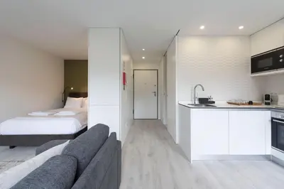 a bedroom with a bed and a couch and a kitchen at LovelyStay - Modern Loft with Gym & Free Parking minutes away from CBD in Porto