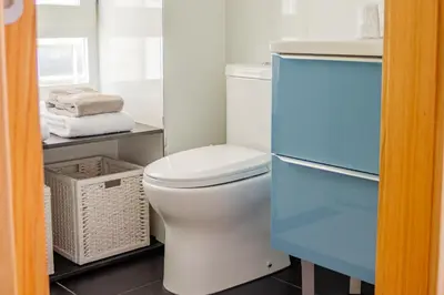 a bathroom with a toilet and a basket and towels at BF Suites & Apartments in Porto