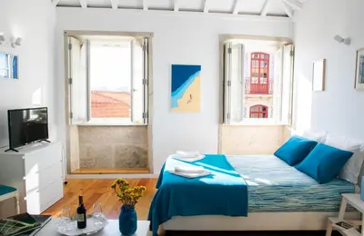 a bedroom with a bed and a tv and two windows at Olival 54 Apartments in Porto