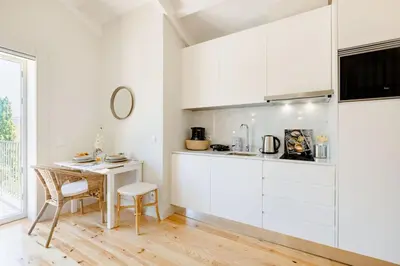a kitchen with white cabinets and a table and chair at Porto Downtown Studio w/ Balcony in Porto