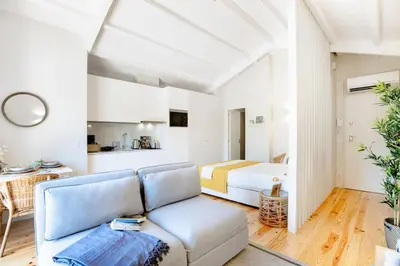a white room with a bed and a kitchen at Porto Downtown Studio w/ Balcony in Porto