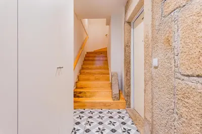 a hallway with wooden stairs and a tile floor at Lemago Porto Apartments - São Bento in Porto