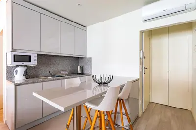 a kitchen with white cabinets and white stools at Lemago Porto Apartments - São Bento in Porto