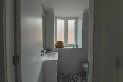 a white bathroom with a sink and a window at Vibrant Host - Heroismo's Metro in Porto